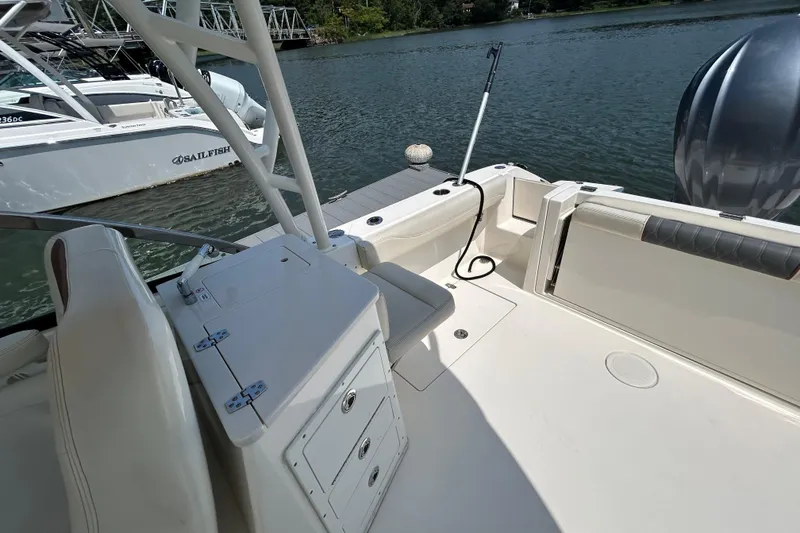 Slide: The Image of 2022 Cobia 240 Dual Console boat interior with seating and storage, docked by the water. - 14