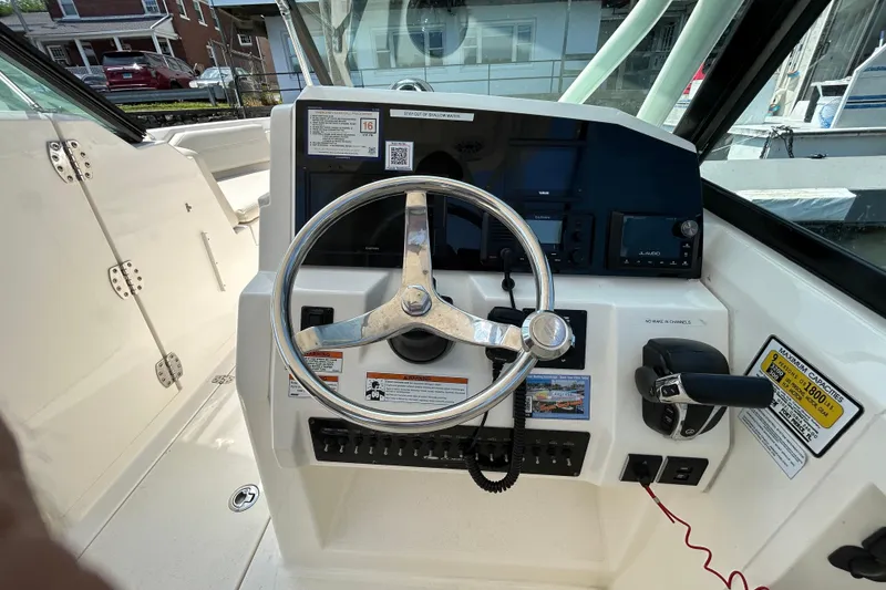 Slide: The Image of 2022 Cobia 240 Dual Console boat helm with steering wheel and control panel. - 16