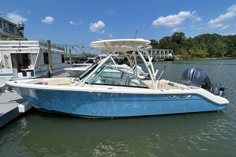 Slide: The Image of 2022 Cobia 240 Dual Console boat docked on a sunny day. - 2