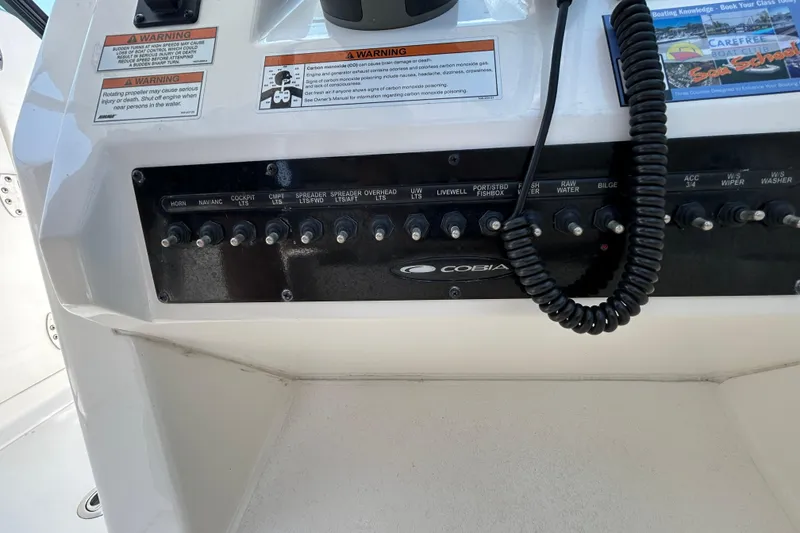Slide: The Image of Control panel of a 2022 Cobia 240 Dual Console boat with labeled switches and warnings. - 6