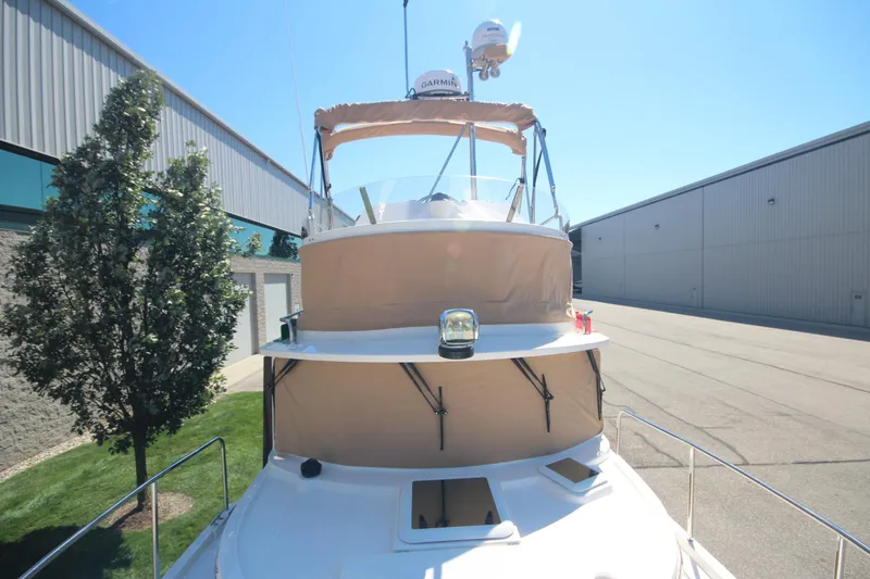 Slide: The Image of 2020 Ranger Tugs R-31 Command Bridge LE with trailer, docked near industrial buildings. - 17