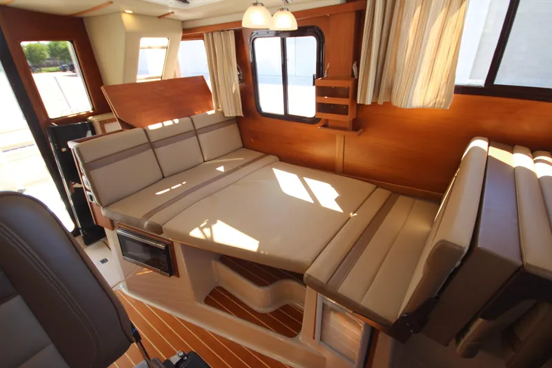 Slide: The Image of 2020 Ranger Tugs R-31 Command Bridge LE interior with convertible seating and wood accents. - 36