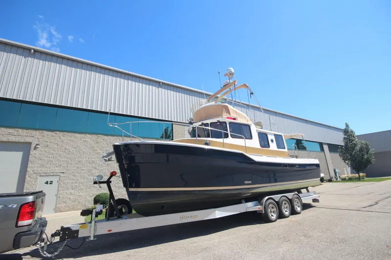 Slide: The Image of 2020 Ranger Tugs R-31 Command Bridge LE on trailer, parked outside industrial building. - 2