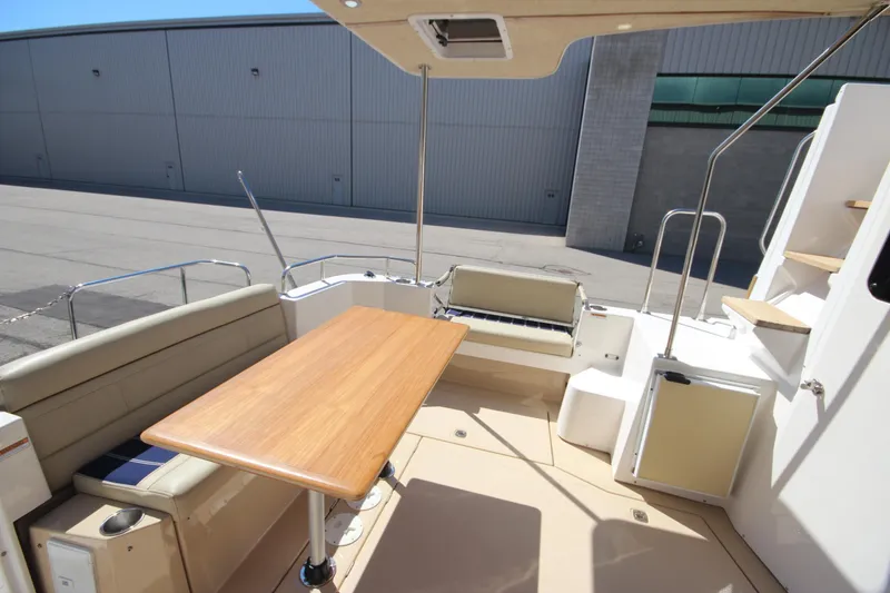 Slide: The Image of 2020 Ranger Tugs R-31 Command Bridge LE interior with seating and table, docked outdoors. - 22