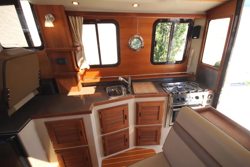 Slide: The Image of 2020 Ranger Tugs R-31 Command Bridge LE interior kitchen with stove, sink, and wooden cabinetry. - 37