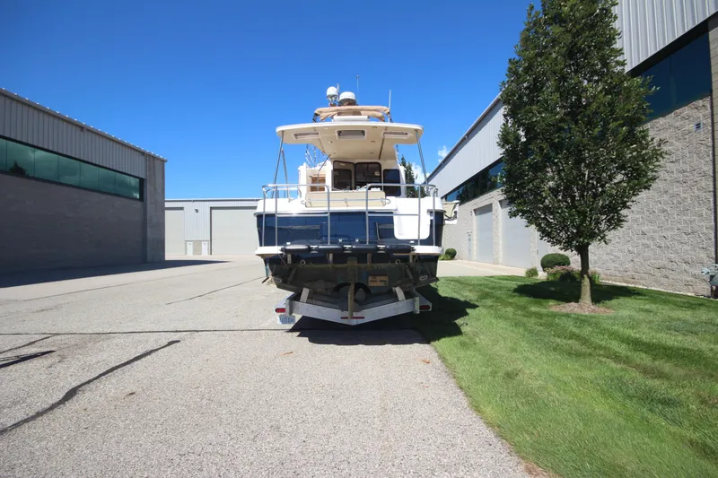 Slide: The Image of 2020 Ranger Tugs R-31 Command Bridge LE on trailer, parked outdoors near industrial buildings. - 5