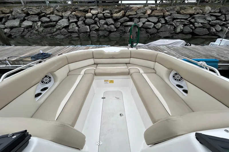 Slide: The Image of 2022 NauticStar 243 DC boat interior with beige seating and speakers, dockside view. - 12