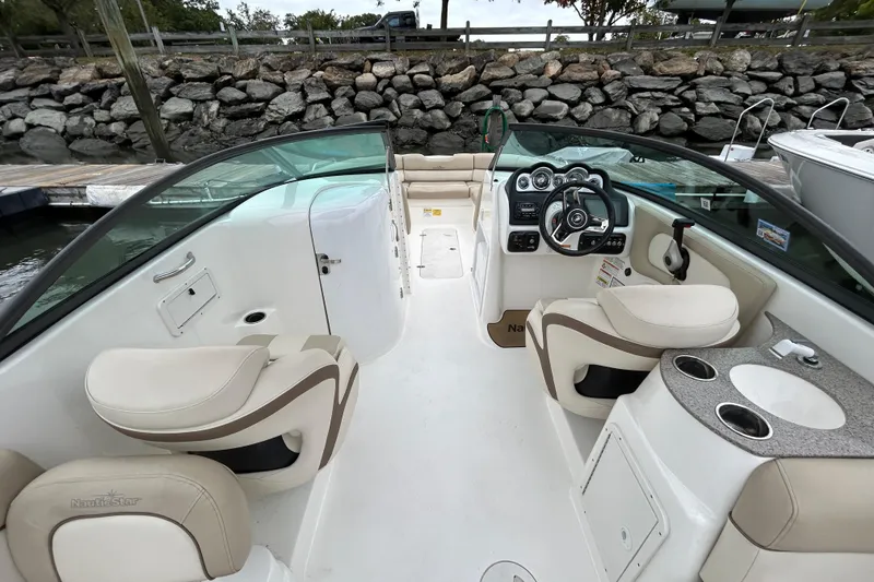 Slide: The Image of 2022 NauticStar 243 DC boat interior with steering wheel, seating, and cup holders. - 8