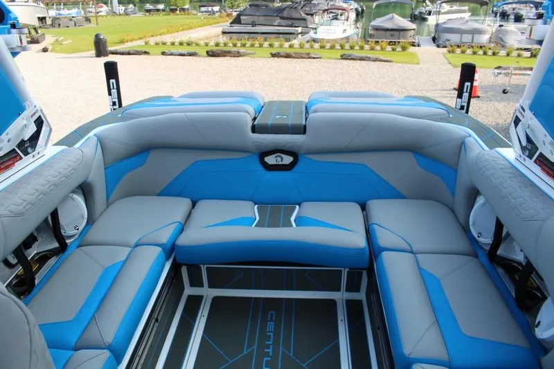 Slide: The Image of 2026 Centurion Ri 230 boat interior with blue and gray seating, docked at marina. - 6