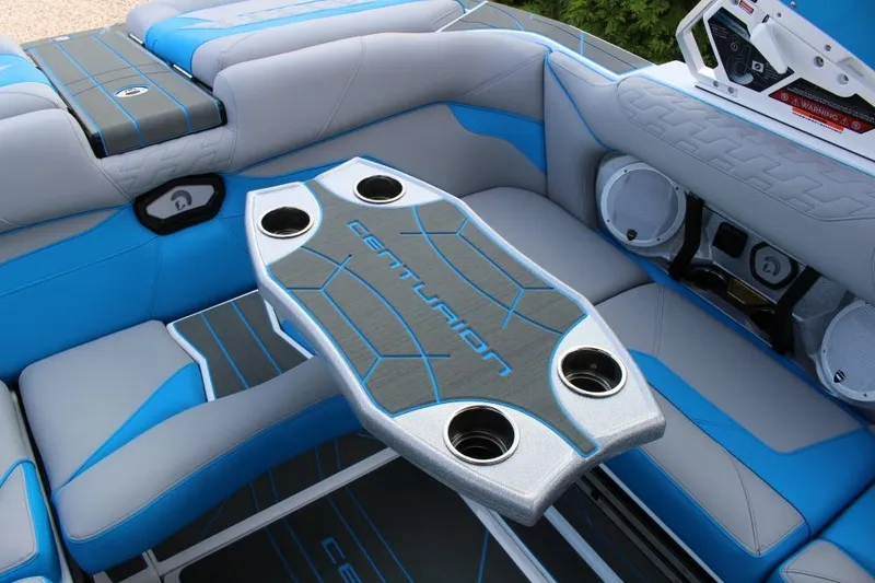 Slide: The Image of 2026 Centurion Ri 230 boat interior with blue and gray seating, cup holders, and speakers. - 8