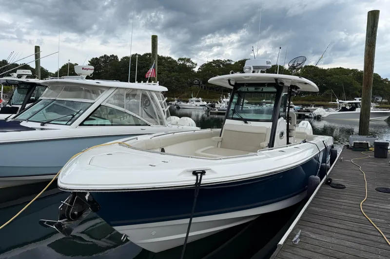 Slide: The Image of 2023 Boston Whaler 330 Outrage docked at marina under cloudy sky. - 1