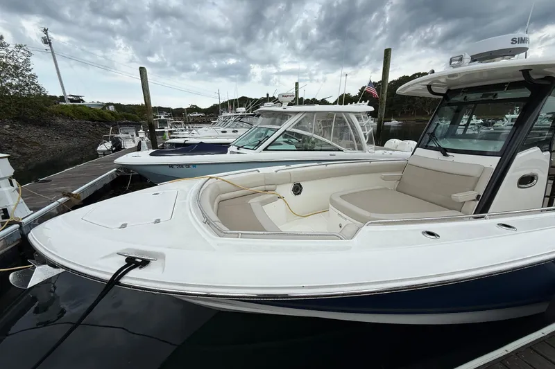 Slide: The Image of 2023 Boston Whaler 330 Outrage docked, showcasing sleek design and spacious seating. - 2