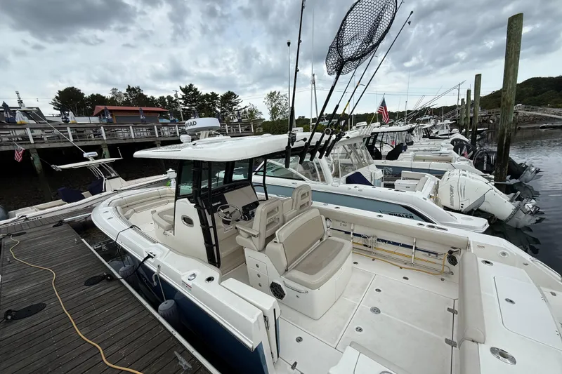 Slide: The Image of 2023 Boston Whaler 330 Outrage docked, featuring fishing rods and spacious seating. - 3