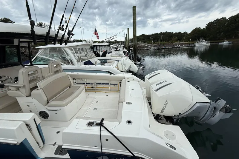 Slide: The Image of 2023 Boston Whaler 330 Outrage docked, featuring Mercury engines and fishing rods. - 5
