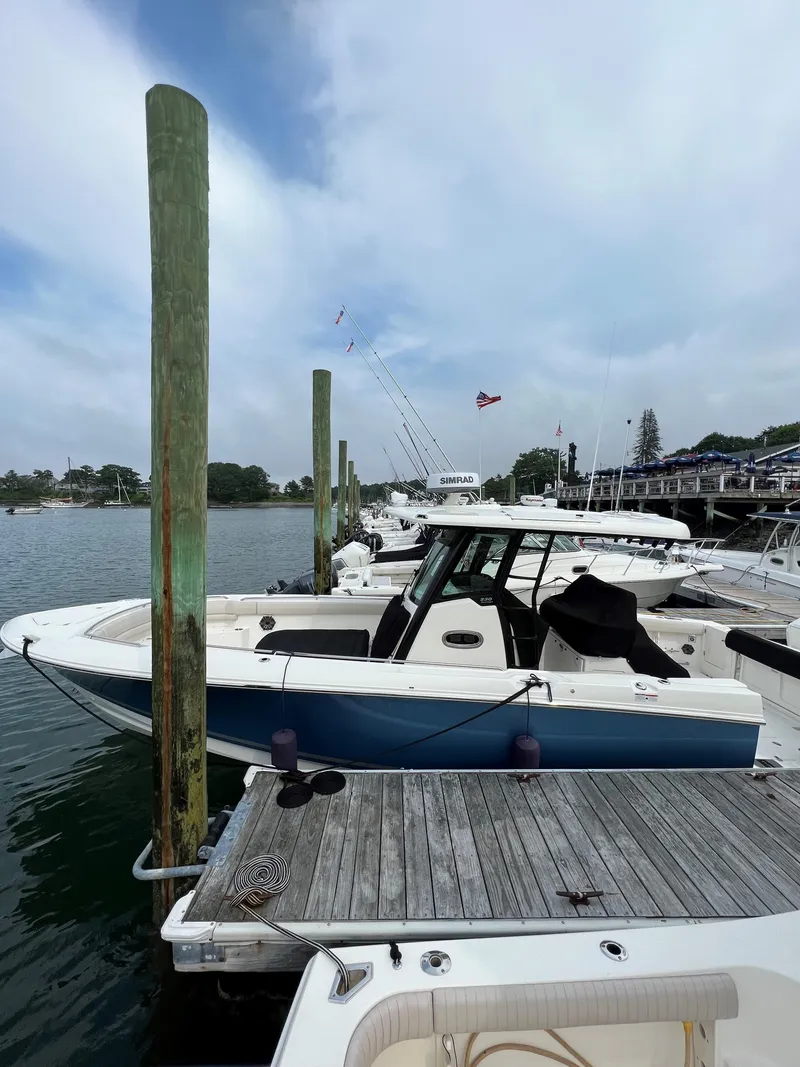 Slide: The Image of 2023 Boston Whaler 330 Outrage docked at a marina under a cloudy sky. - 7