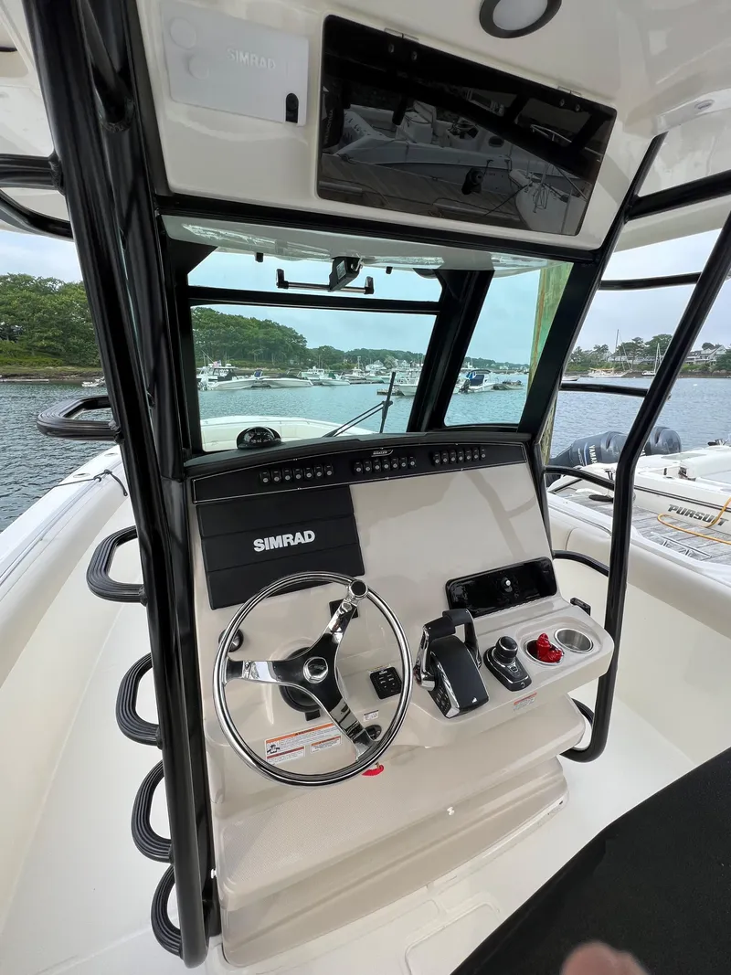 Slide: The Image of 2023 Boston Whaler 330 Outrage helm with Simrad electronics, steering wheel, and controls. - 8
