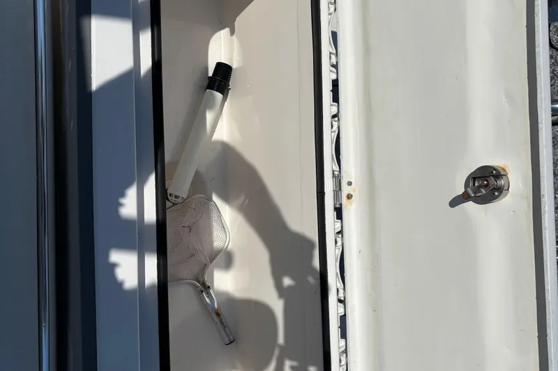 Slide: The Image of Storage compartment on a 2022 Twin Vee 240 GFX CC boat with fishing net and handle. - 15