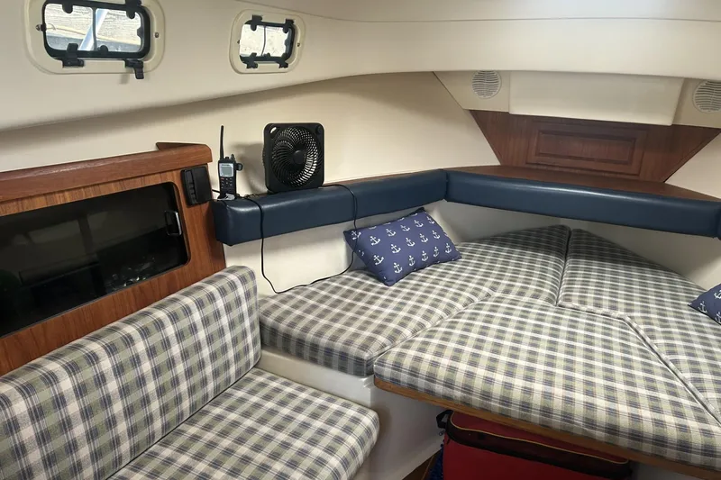 Slide: The Image of 1998 Mainship Pilot 30 cabin interior with plaid seating and nautical-themed pillows. - 19