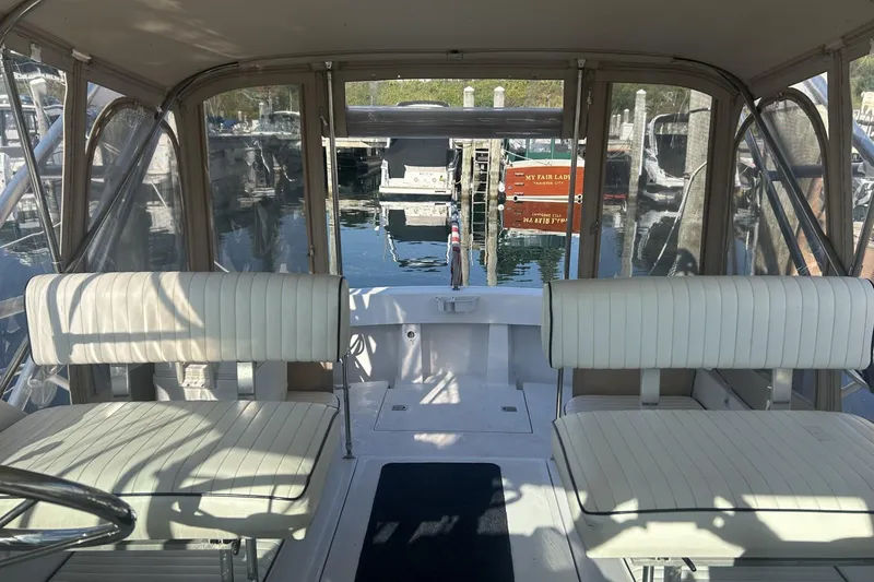 Slide: The Image of 1998 Mainship Pilot 30 interior with white seating, docked at marina. - 9