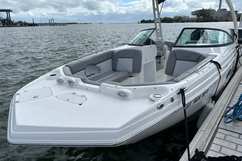 The Image of 2022 NauticStar 243 DC boat docked on a calm waterfront under cloudy skies. - 1