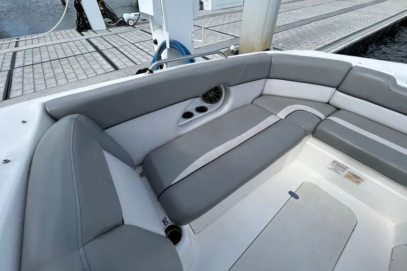Slide: The Image of 2022 NauticStar 243 DC boat interior with gray seating and cup holders at dock. - 13