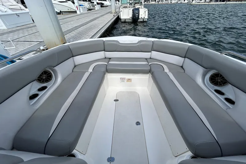 Slide: The Image of 2022 NauticStar 243 DC boat interior with gray seating and cup holders at dock. - 14
