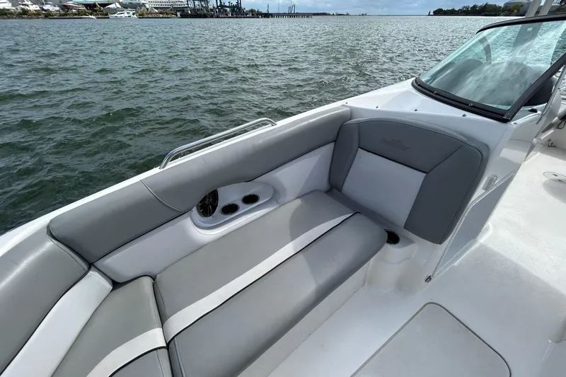 Slide: The Image of 2022 NauticStar 243 DC boat interior with gray seating, cup holders, and waterfront view. - 15
