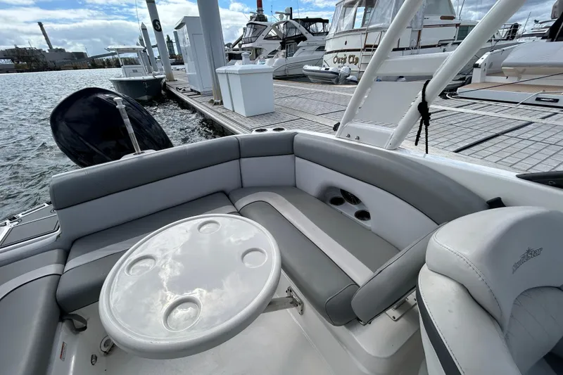 Slide: The Image of 2022 NauticStar 243 DC boat interior with seating and table at marina dock. - 20