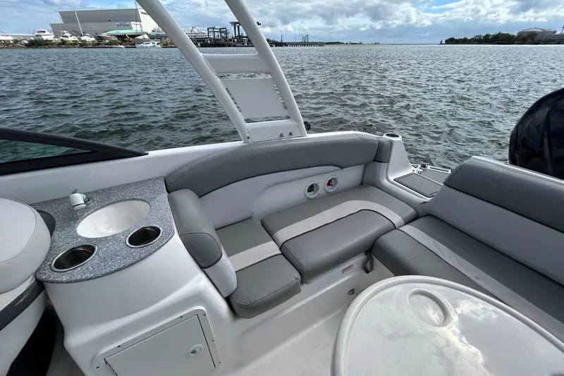 Slide: The Image of 2022 NauticStar 243 DC boat interior with seating and cup holders on a calm water backdrop. - 21