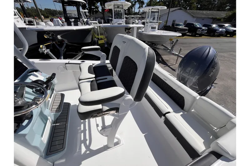 Slide: The Image of 2026 Tidewater 220 LXF boat interior with seating and steering wheel, parked outdoors. - 14