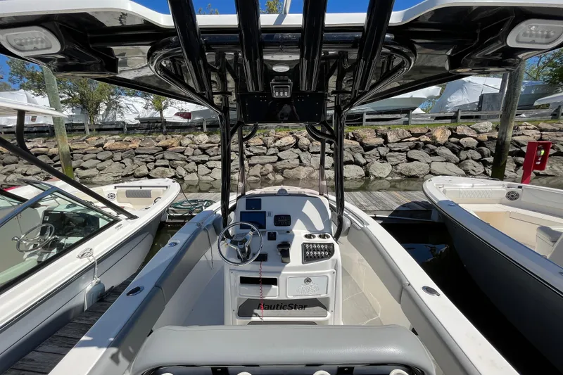 Slide: The Image of 2021 NauticStar 2102 Legacy boat interior with steering wheel and dashboard, docked at marina. - 12