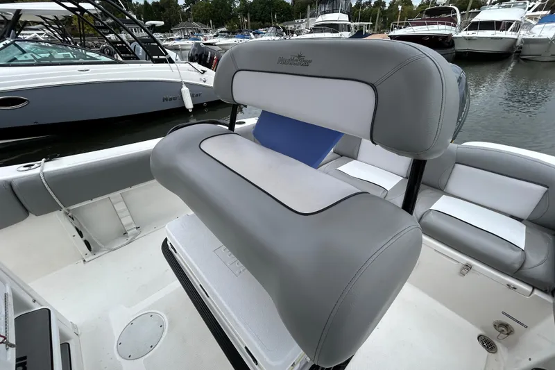 Slide: The Image of 2021 NauticStar 2102 Legacy boat interior with gray seating at marina. - 19