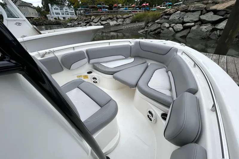 Slide: The Image of 2021 NauticStar 2102 Legacy boat with gray cushioned seating, docked by rocky shoreline. - 26
