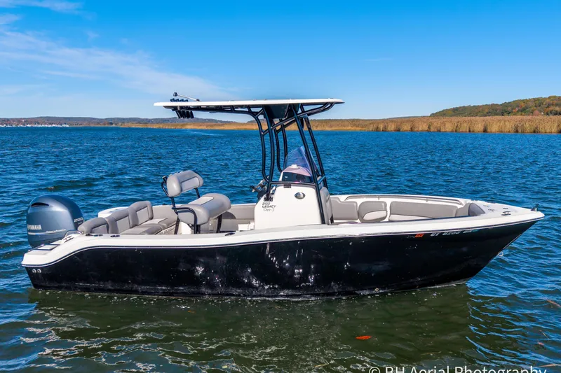 Slide: The Image of 2021 NauticStar 2102 Legacy boat on a serene lake with clear blue skies. - 4