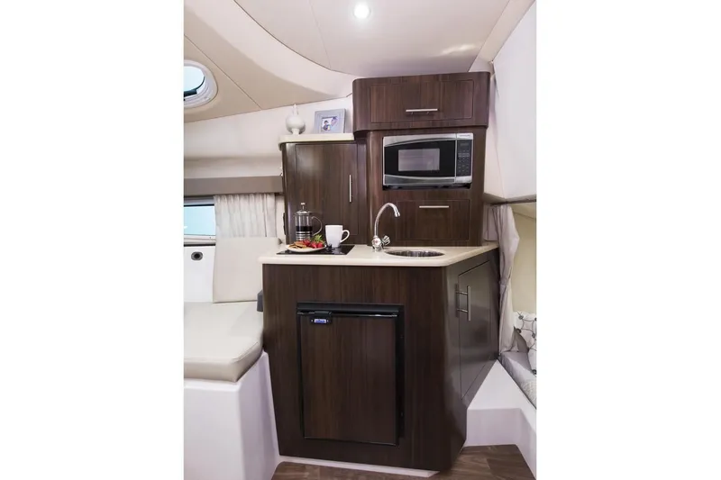 Slide: The Image of 2019 Regal 28 Express boat interior kitchenette with microwave, sink, and mini-fridge. - 13