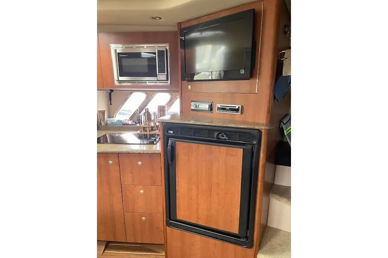 Slide: The Image of 2011 Cruisers Yachts 360 Express interior with microwave, TV, and fridge in wooden cabinetry. - 24