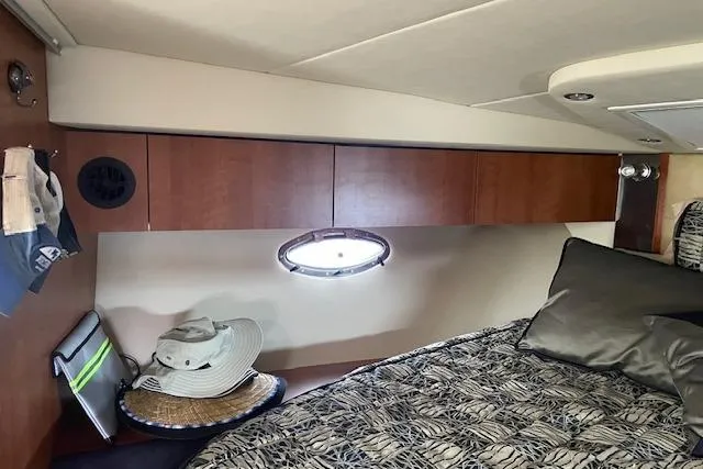 Slide: The Image of 2011 Cruisers Yachts 360 Express cabin interior with bed, wooden cabinets, and porthole window. - 34