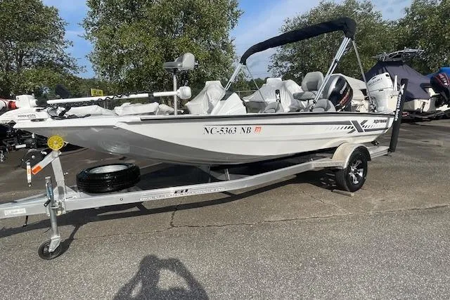 Slide: The Image of 2023 Xpress H17 boat on trailer, parked outdoors, with trees in the background. - 8