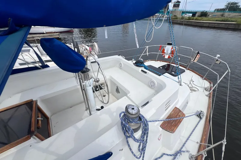 Slide: The Image of 1985 C&C Landfall 39 sailboat cockpit with blue cover, docked by a calm waterway. - 7