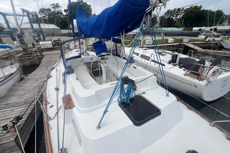 Slide: The Image of 1985 C&C Landfall 39 sailboat docked, featuring blue sail cover and spacious cockpit. - 9
