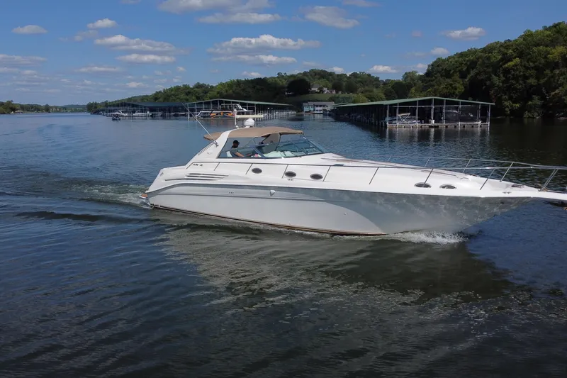 Slide: The Image of 1997 Sea Ray 450 Sundancer cruising on a serene lake under a clear blue sky. - 11