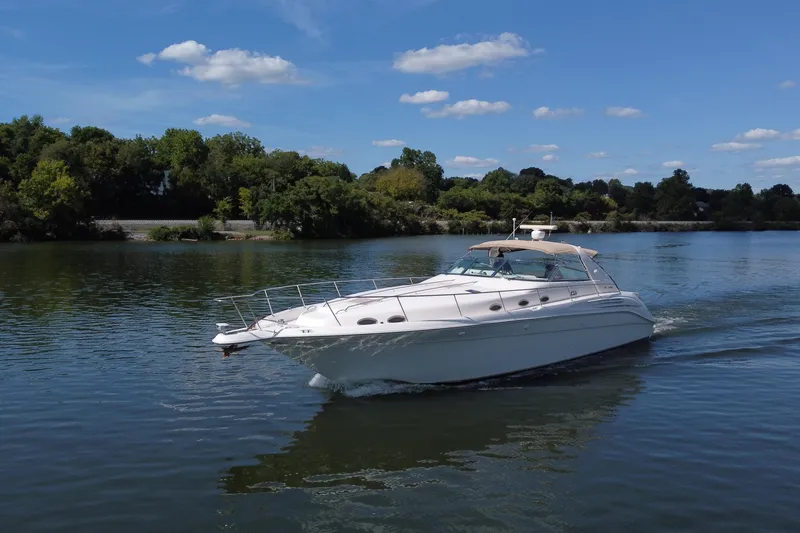 Slide: The Image of 1997 Sea Ray 450 Sundancer cruising on a serene lake under a clear blue sky. - 16
