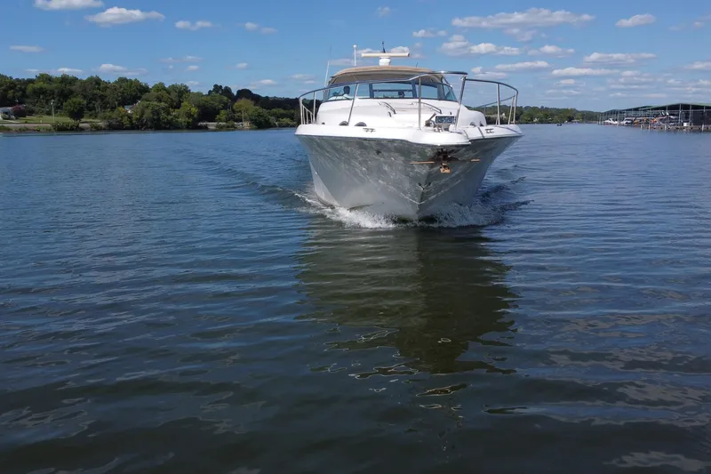 Slide: The Image of 1997 Sea Ray 450 Sundancer cruising on a calm lake under a clear blue sky. - 23