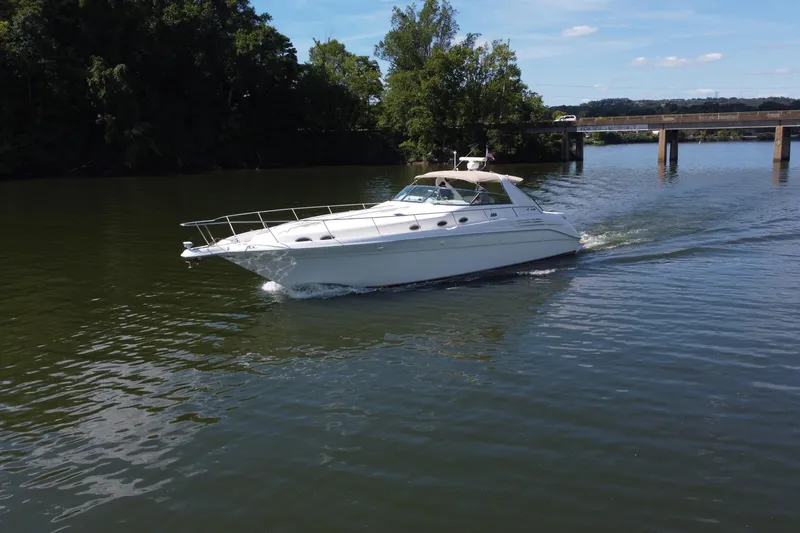Slide: The Image of 1997 Sea Ray 450 Sundancer cruising on a serene river near a bridge. - 5