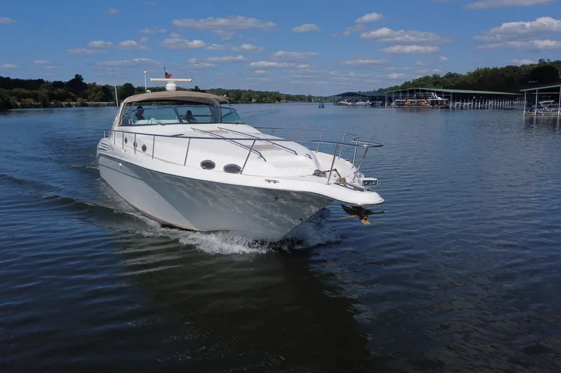 Slide: The Image of 1997 Sea Ray 450 Sundancer cruising on a calm lake under a clear blue sky. - 7