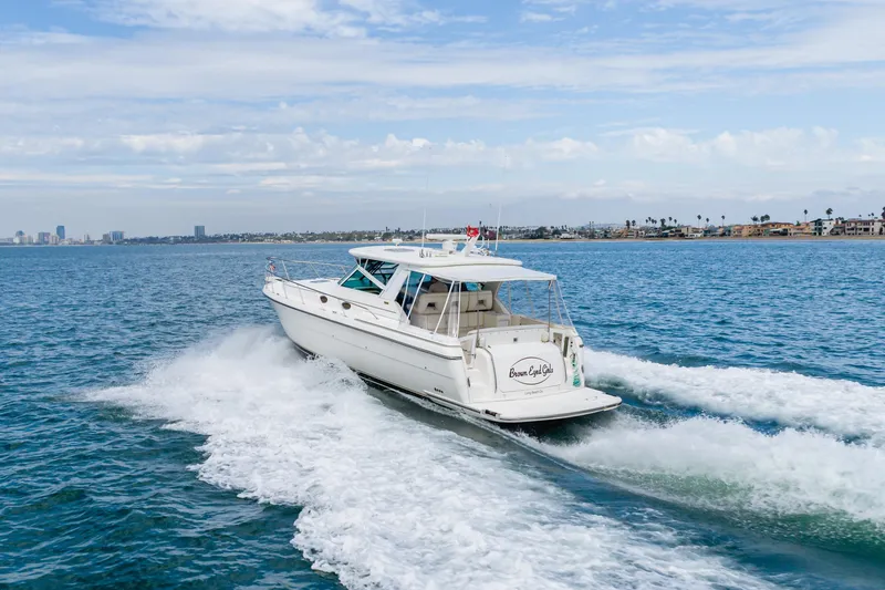 Slide: The Image of 2004 Tiara Yachts 4000 Express cruising on open water, coastal cityscape in background. - 10