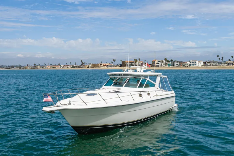 Slide: The Image of 2004 Tiara Yachts 4000 Express cruising on blue ocean near coastal homes. - 2