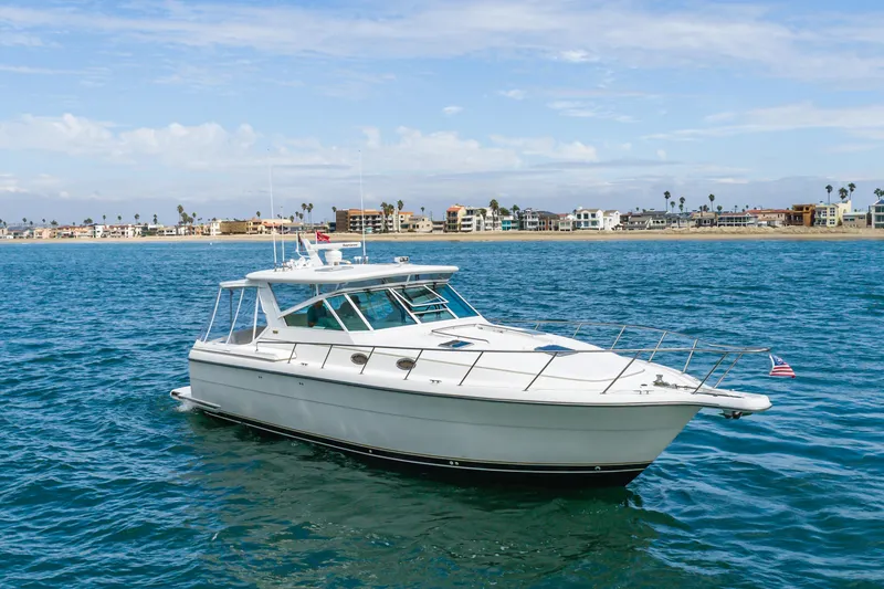 Slide: The Image of 2004 Tiara Yachts 4000 Express cruising on blue ocean near coastal homes. - 3