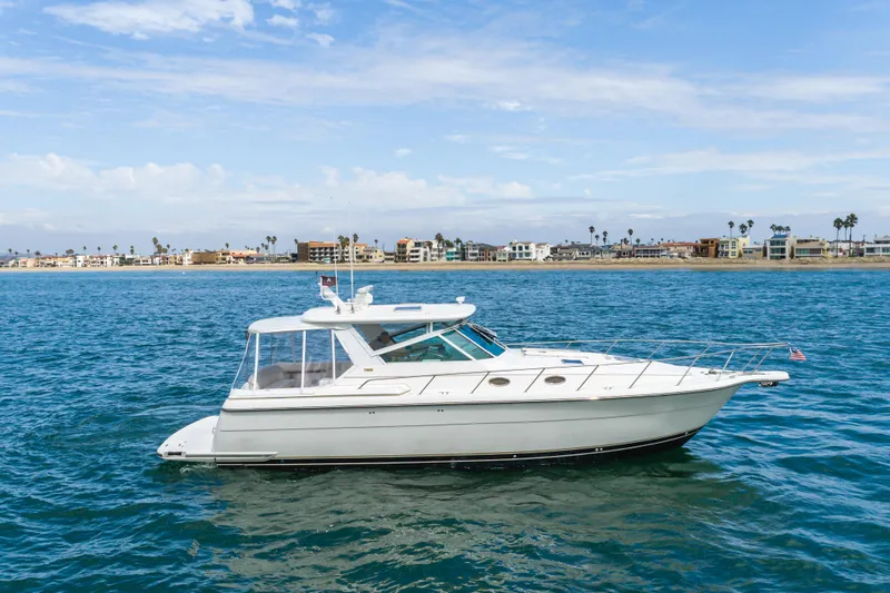 Slide: The Image of 2004 Tiara Yachts 4000 Express cruising on blue ocean near coastal homes. - 4