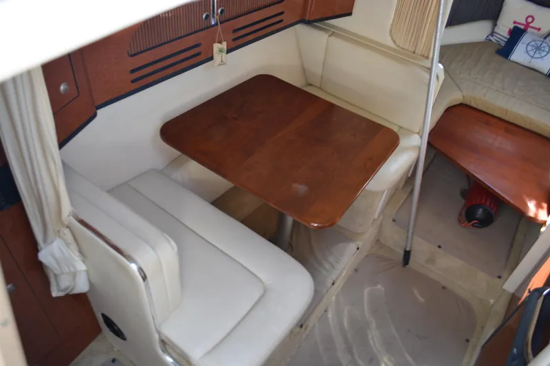 Slide: The Image of 2005 Sea Ray 280 Sundancer cabin interior with wooden table and cushioned seating. - 14